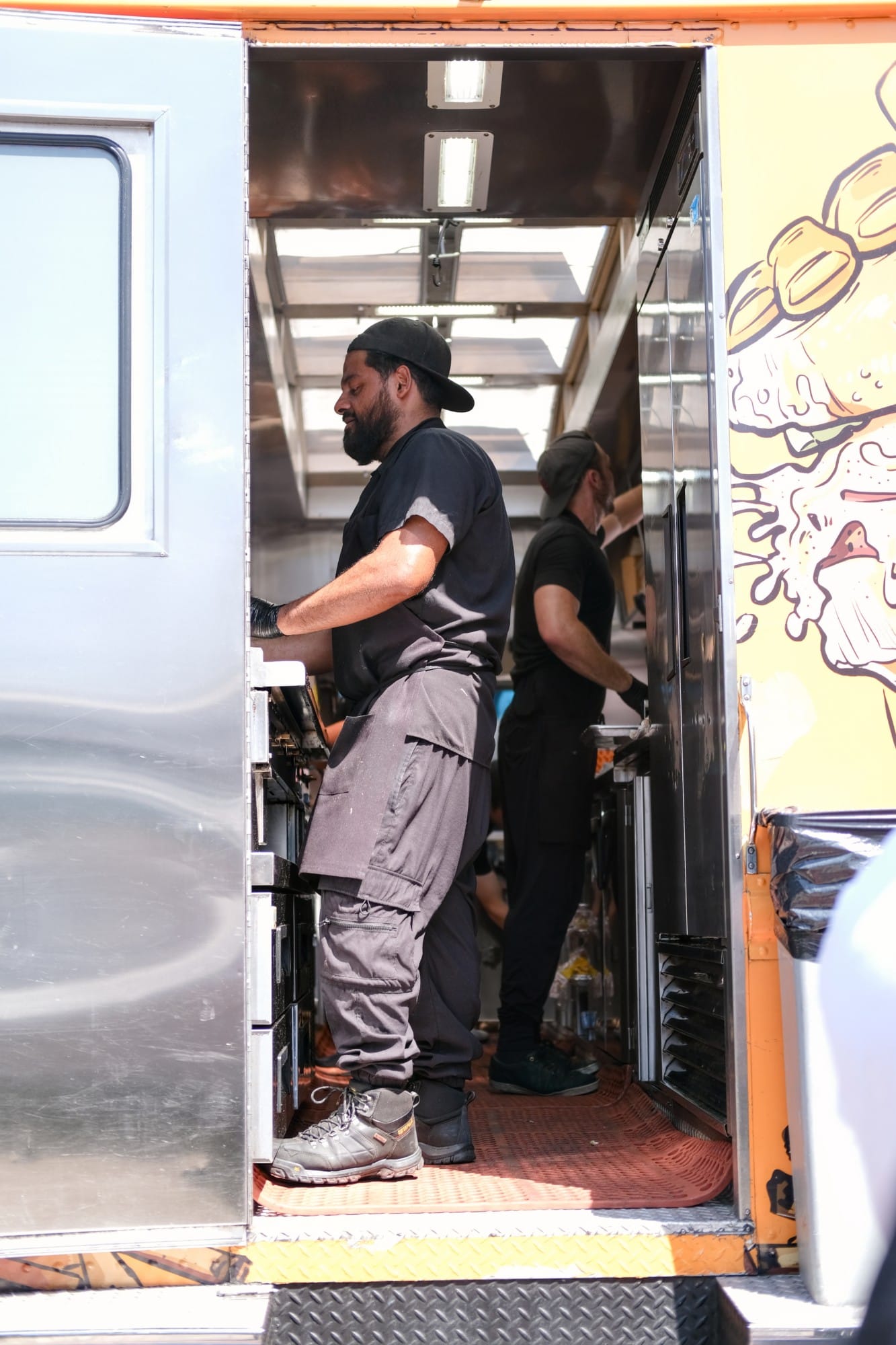 A cook working the grill inside a food truck at the summit