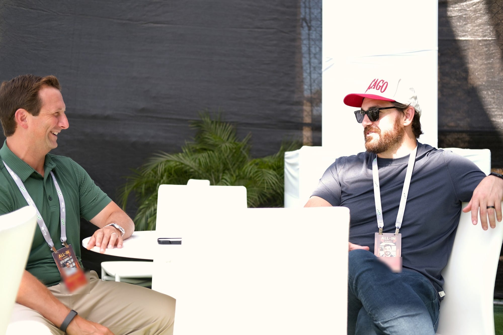 Two attendees laughing mid-conversation at a table in the lounge