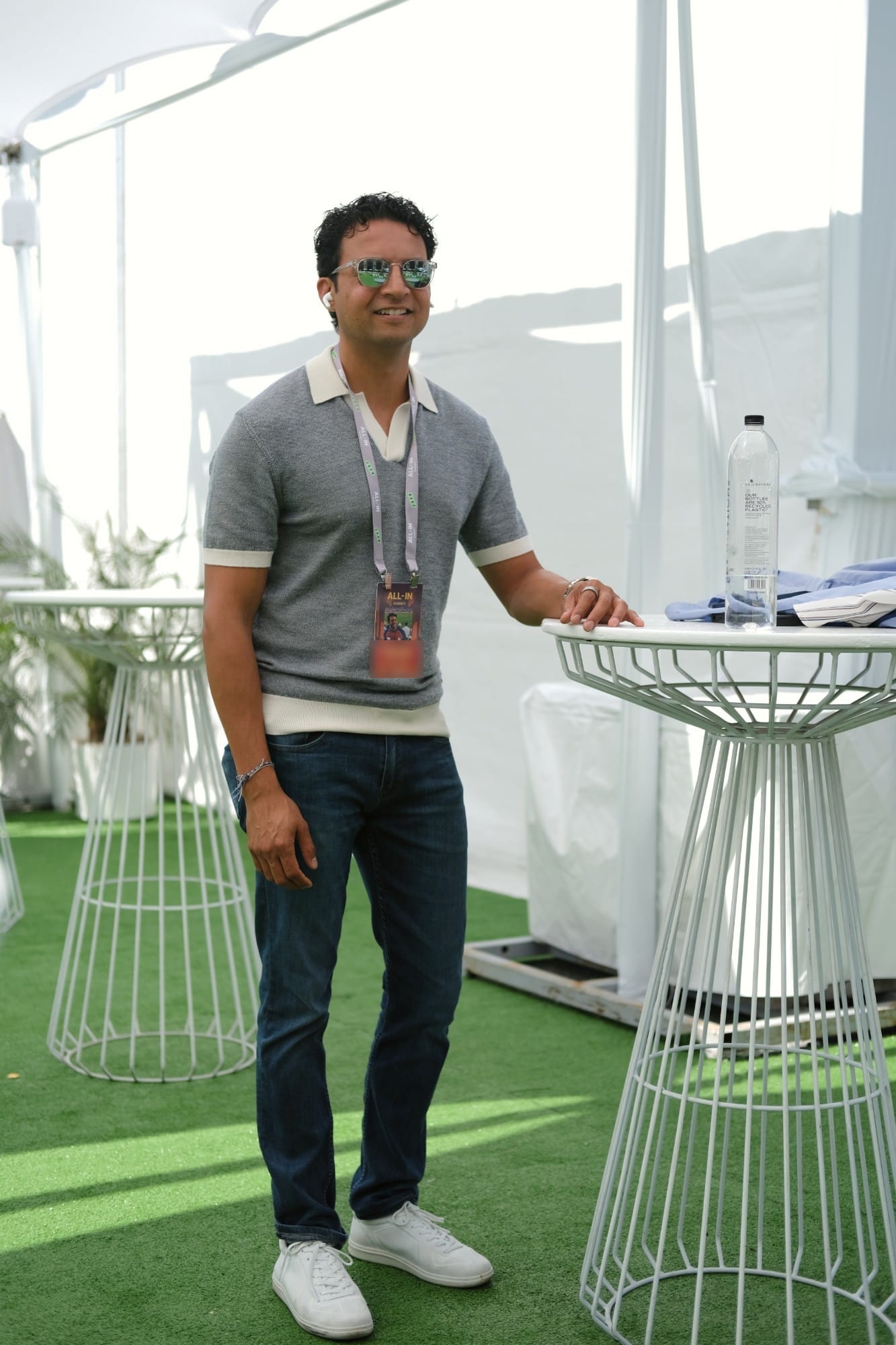 An attendee smiling beside a white wire high-top table in a tent