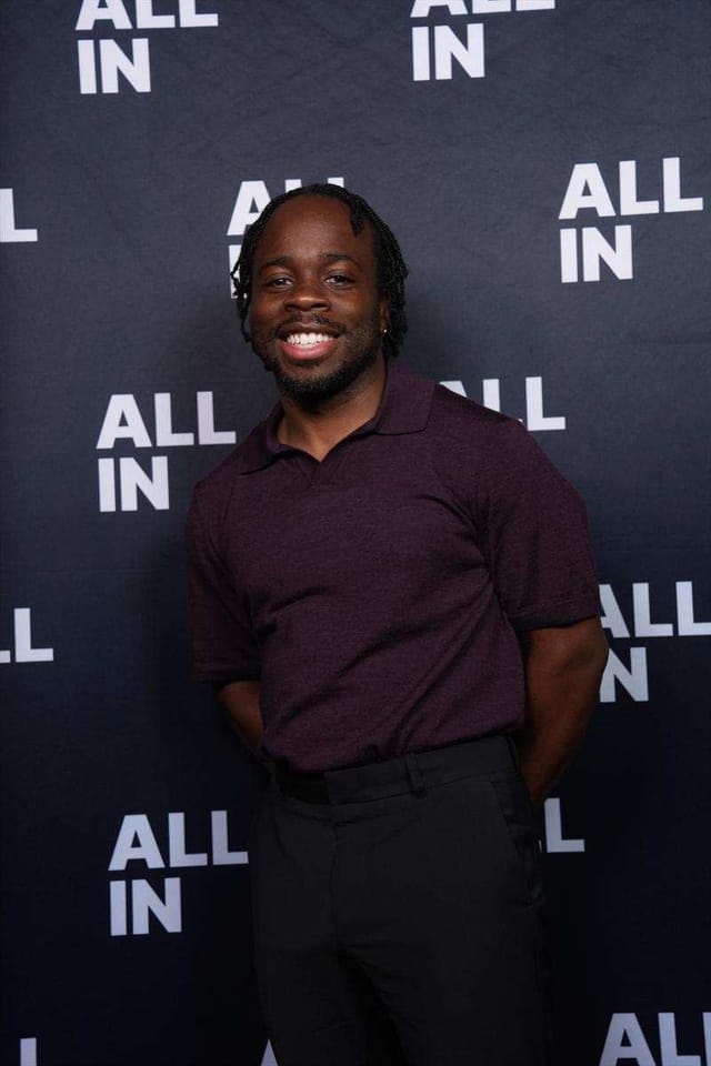 Carrington smiling in front of the All-In step-and-repeat backdrop